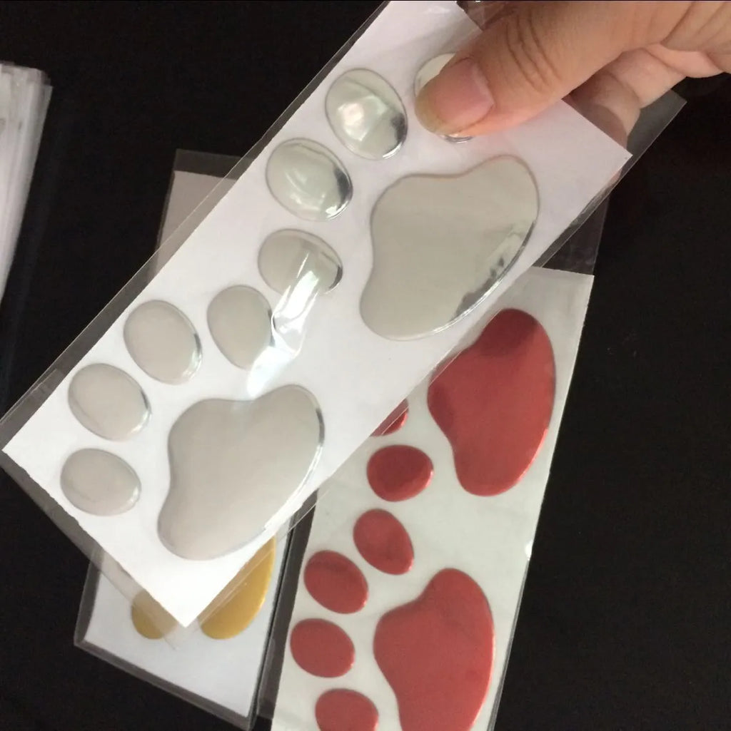 PVC car sticker shaped like a hand holding a brush, decorated with dog footprints pattern.