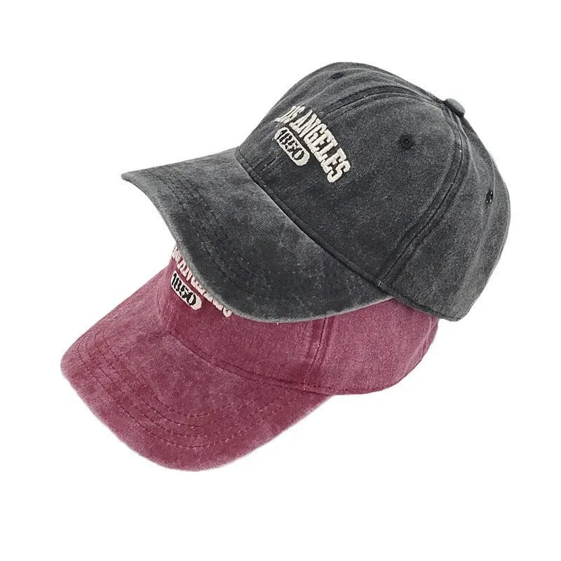 Retro distressed beige cap with adjustable strap and embroidered letters on a conical crown.