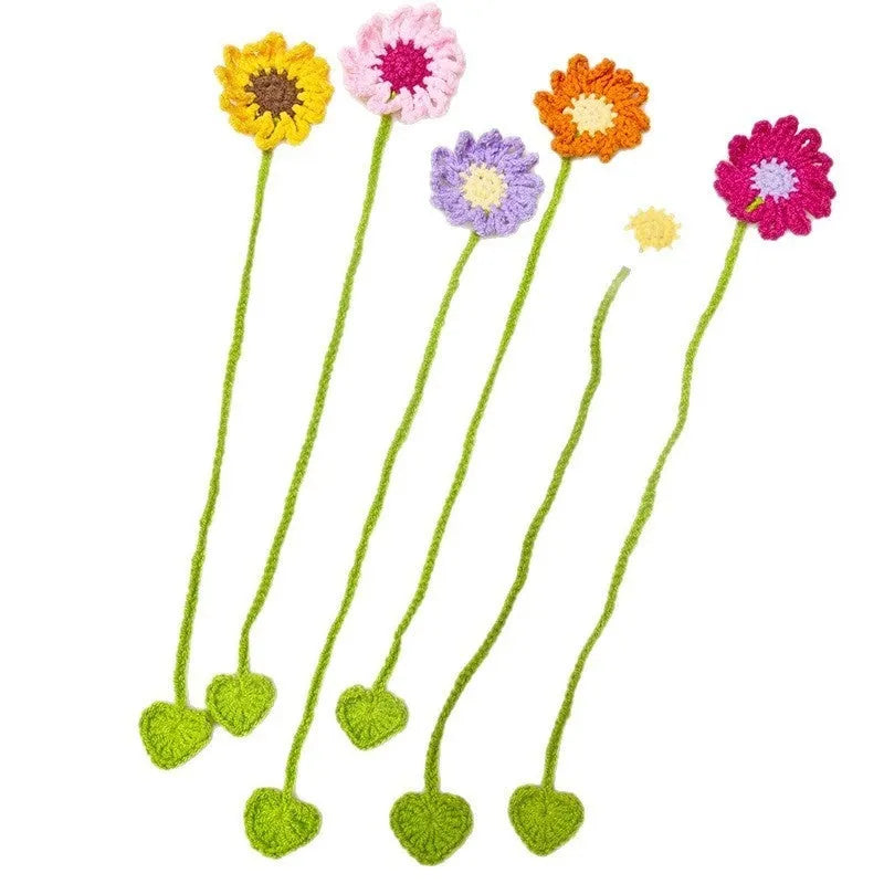 Close-up of a hand-crocheted yellow daisy wool bookmark with a flexible wire core on an open book.