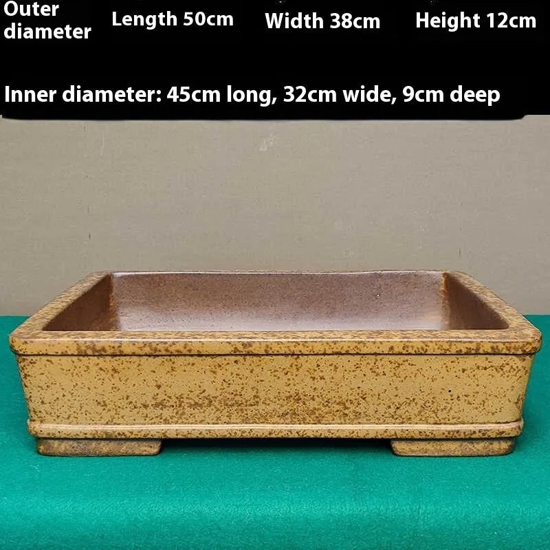 Straight-sided shallow rectangular Yixing flower pot in natural purple sand clay on a wooden surface.
