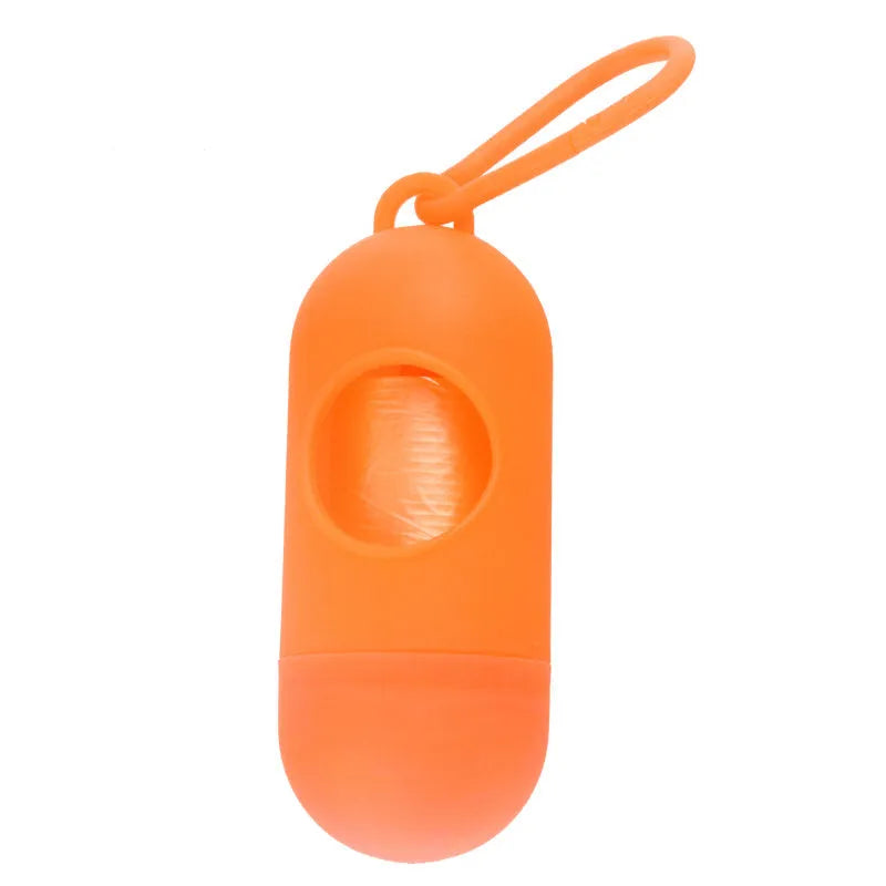 Compact black dog waste bag holder with a metal hook and Velcro strap, shown next to a roll of bags.