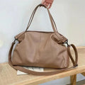 Large soft surface casual messenger bag in black showing horizontal shape and shoulder strap.