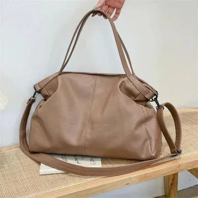 Large soft surface casual messenger bag in black showing horizontal shape and shoulder strap.