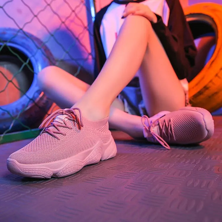 Women's white fly-knit sports shoes with thick rubber sole and front strap.