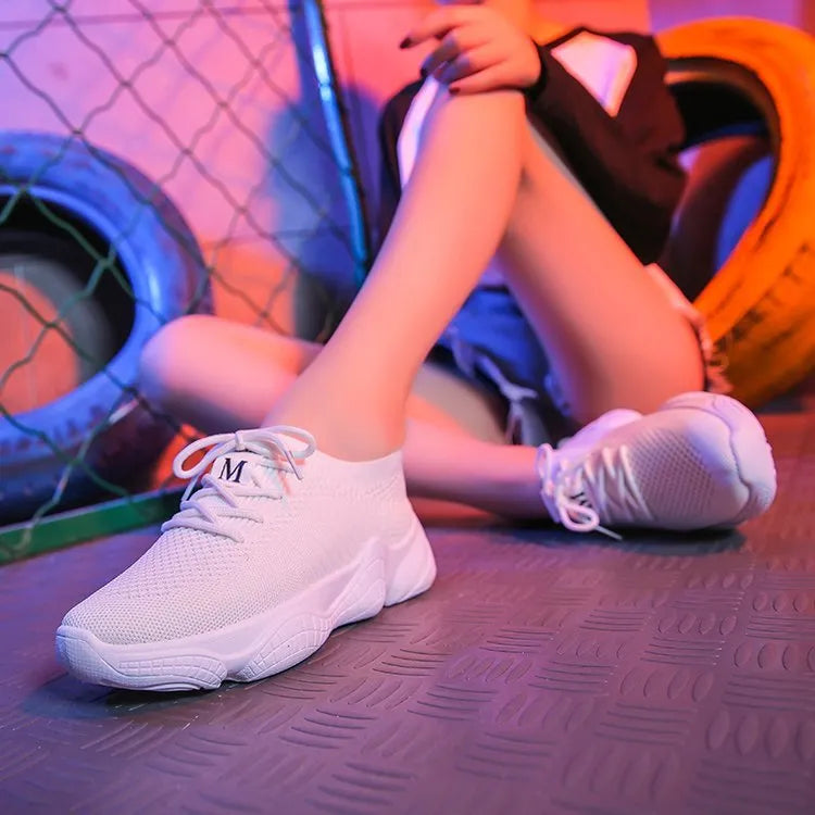 Women's white fly-knit sports shoes with thick rubber sole and front strap.