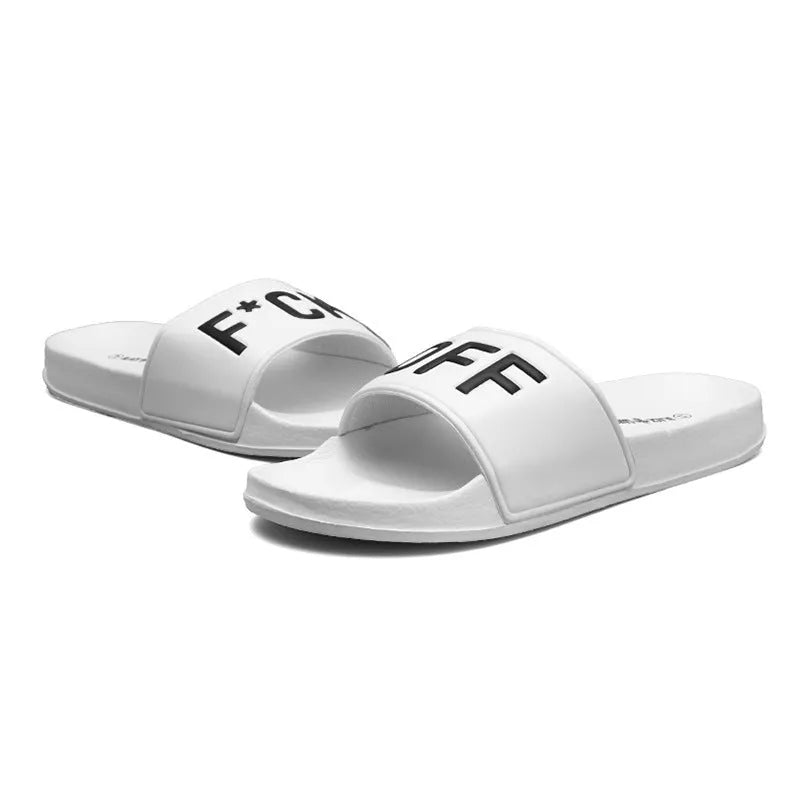 A pair of black open-toe men's slippers with a visible rubber sole, shown on a wooden floor.