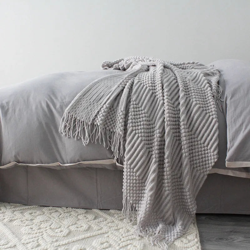 Small grey polyester nap blanket folded, showing its 127x170cm size on a sofa.