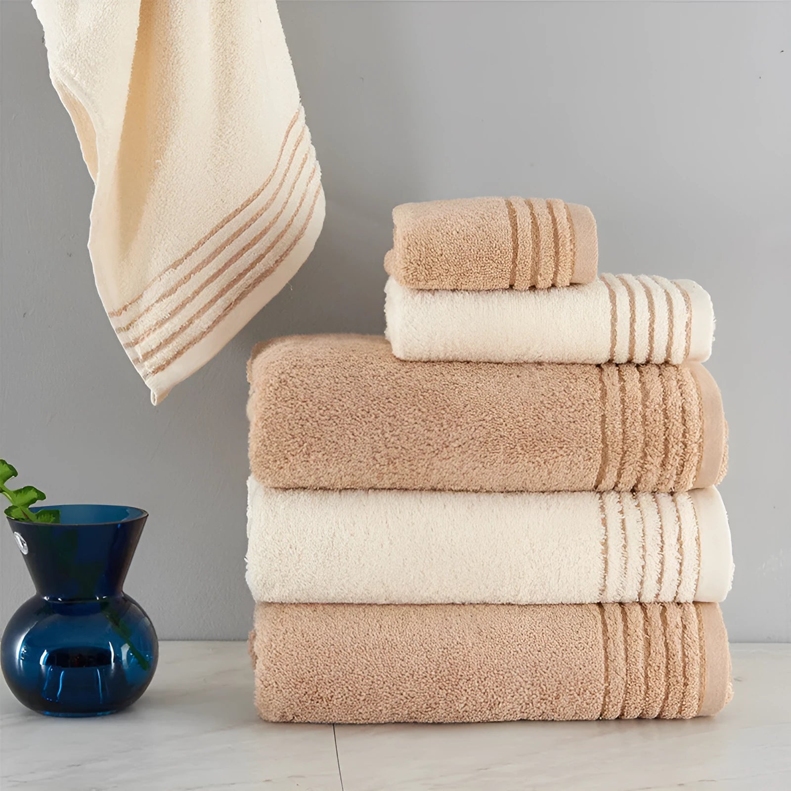 Set of three cotton towels in beige and brown including large bath towel, hand towel, and small washcloth
