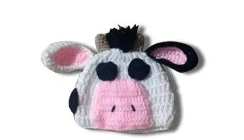 Hand-knitted white baby cow suit with hat and trousers for a newborn.