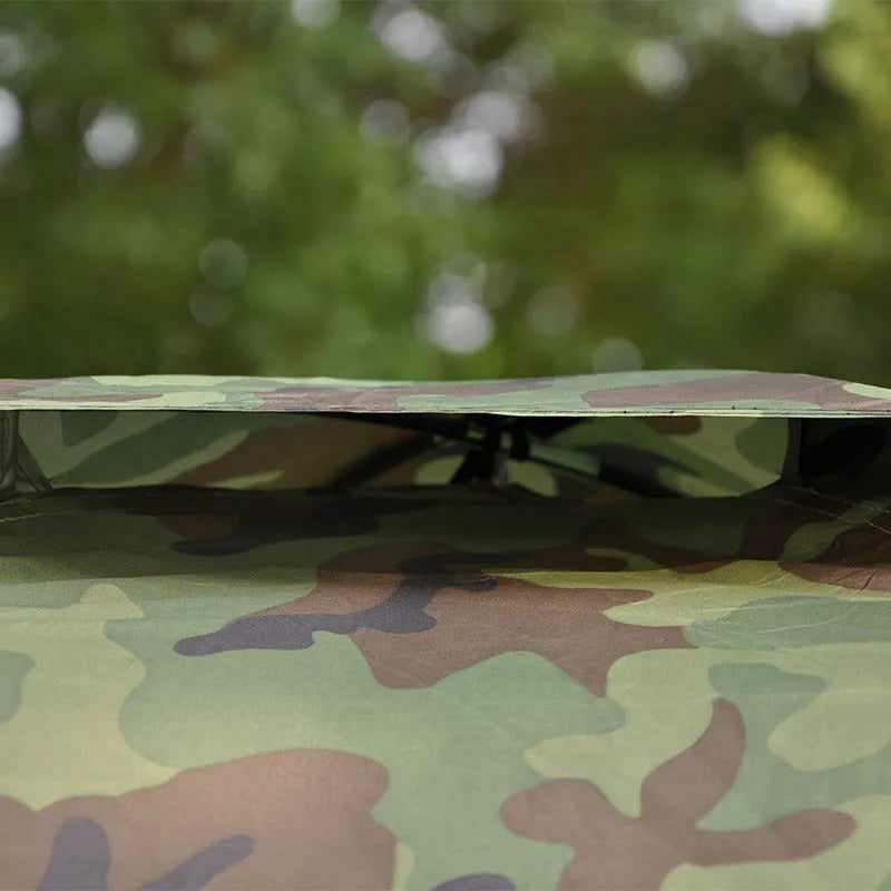 Green camouflage two-person tent with mesh windows, pitched outdoors.
