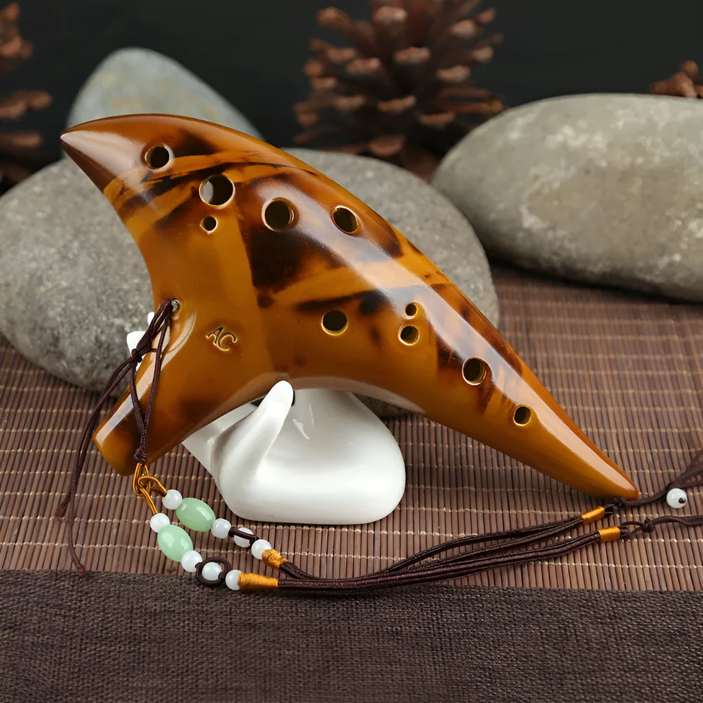 Yellow 12-hole ceramic Alto C ocarina with smoldering finish and lanyard on a surface