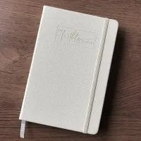 A5 black hardback lined notebook on a wooden desk with elastic closure closed