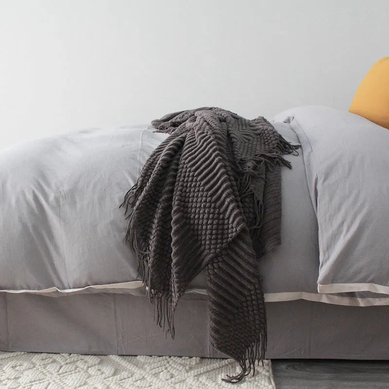 Small grey polyester nap blanket folded, showing its 127x170cm size on a sofa.