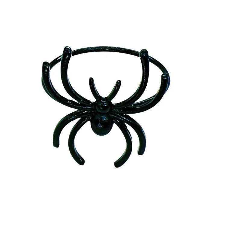 Six black alloy spider-shaped napkin rings on a dark table, showing detailed legs and a 5cm height.