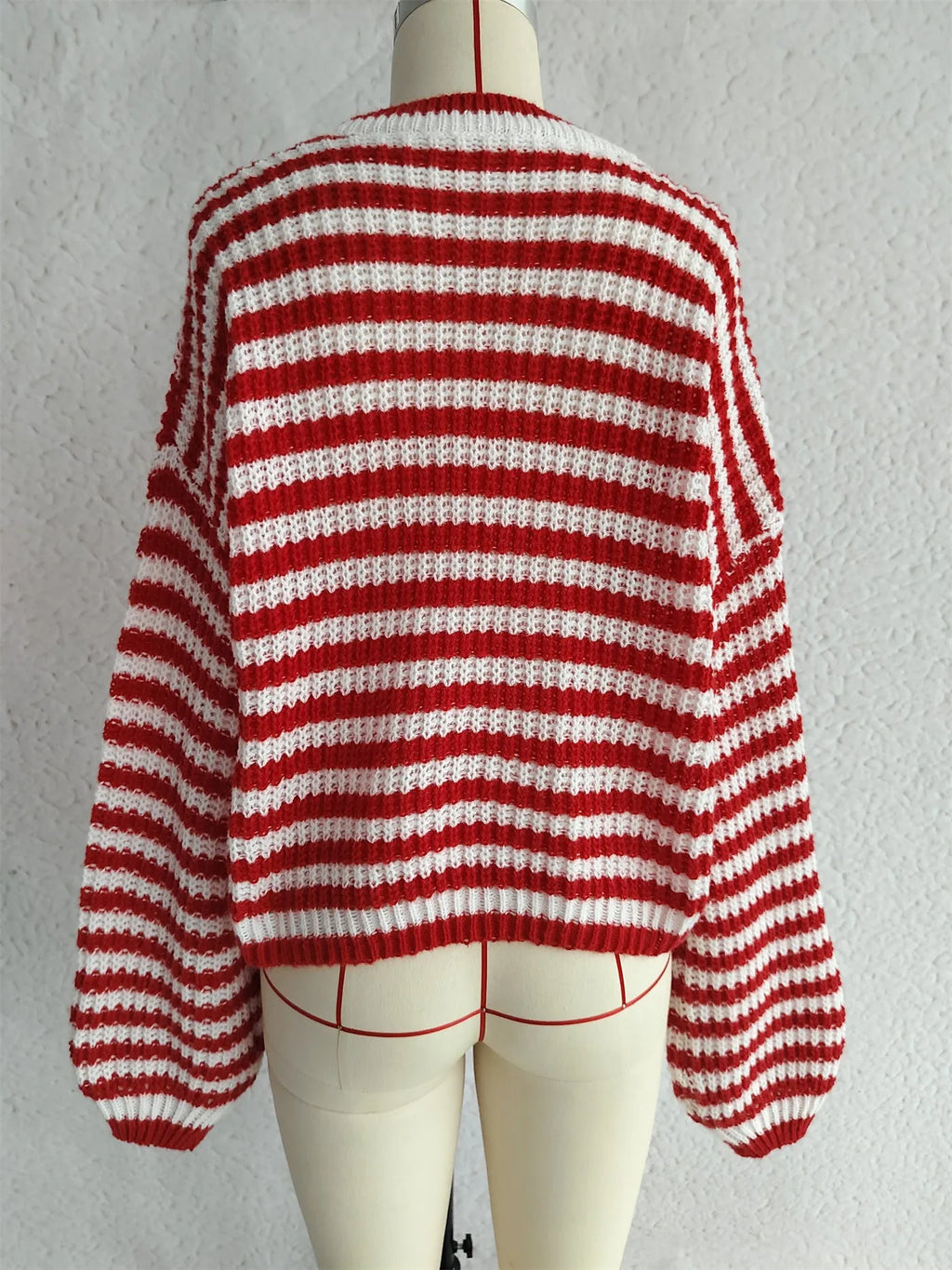 A woman's loose-fitting, long-sleeve stripe pullover sweater on a hanger in a khaki colour.