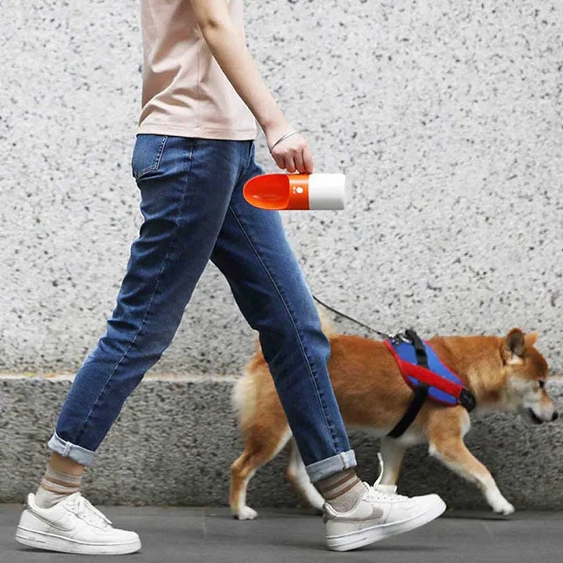 Moestar rocket-shaped pet drinking cup in white with grey or orange accents showing one-button lock mechanism