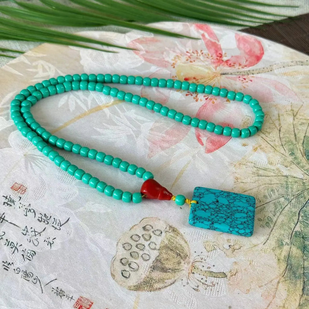 Close-up of a hand-woven mesh flower turquoise pendant on an adjustable ball bead necklace.