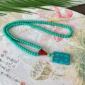Close-up of a hand-woven mesh flower turquoise pendant on an adjustable ball bead necklace.