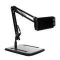 Black universal phone stand with long metal arm and circular base on a wooden desk