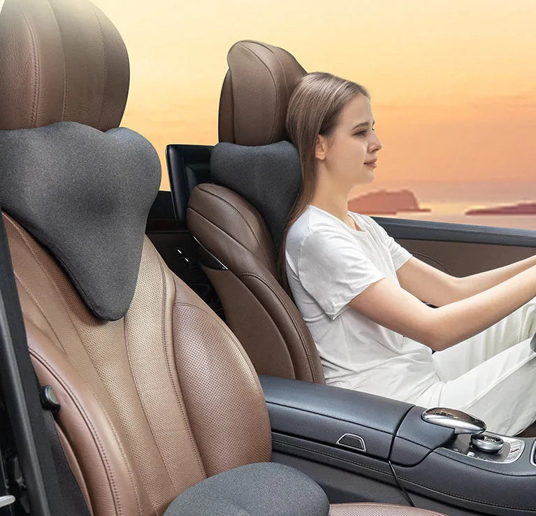 Dark grey memory foam car neck pillow resting on a car seat headrest.