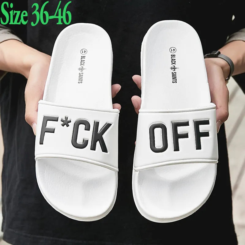 A pair of black open-toe men's slippers with a visible rubber sole, shown on a wooden floor.