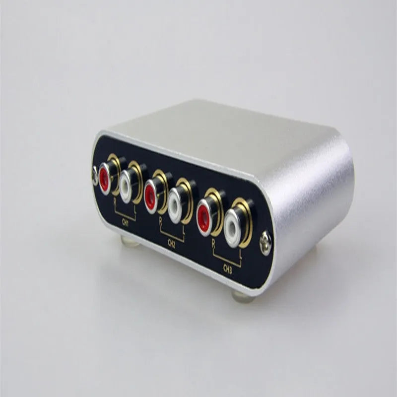 Silver aluminium audio source selector switch unit with front panel button and infrared remote.