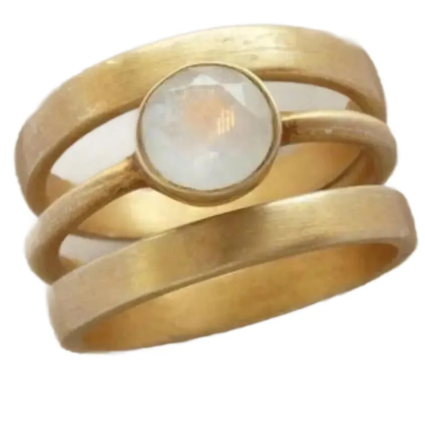 Gold geometric titanium steel ring with a white chalcedony stone inlaid in a hollow design on a finger.