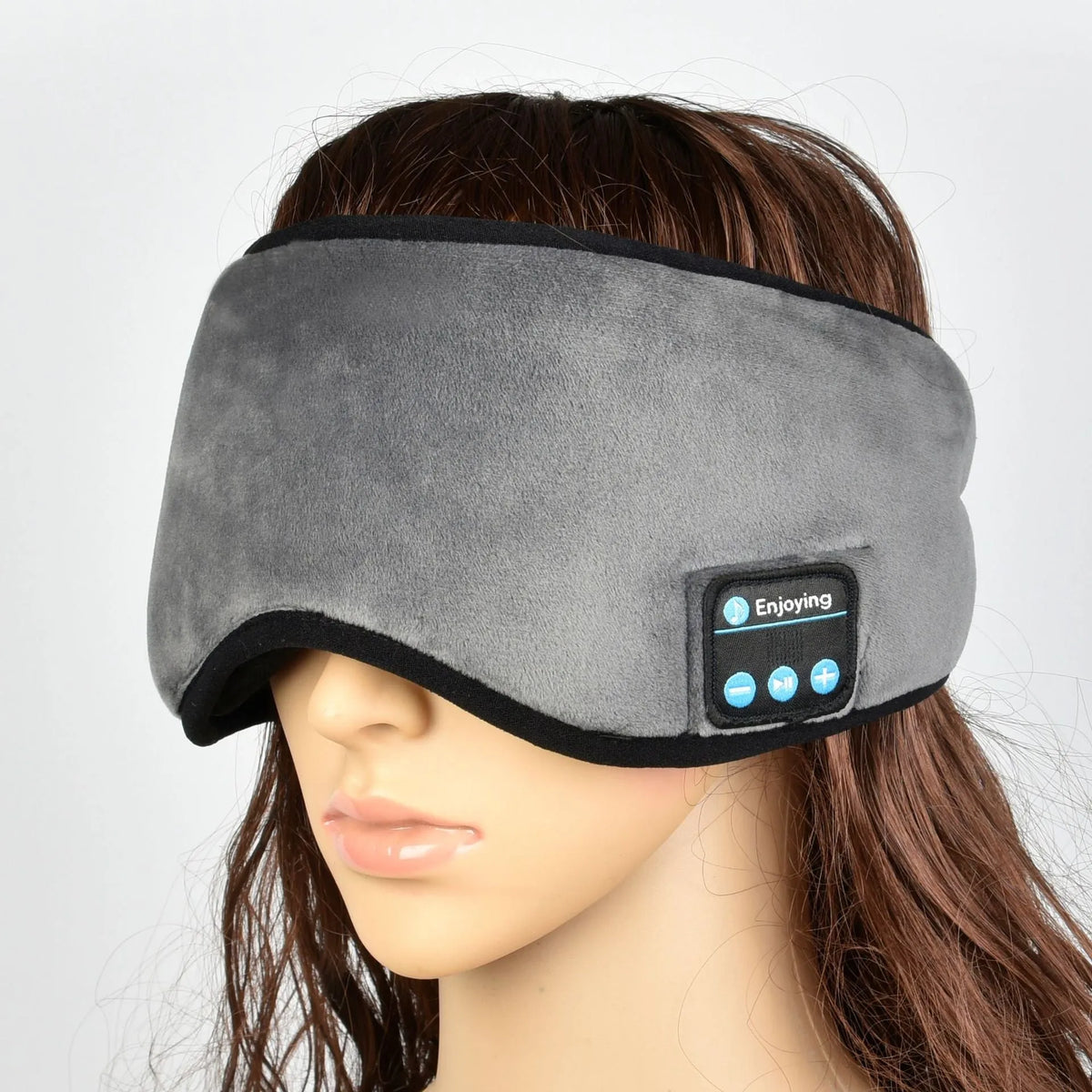 Soft satin sleep eye mask in black with adjustable strap lying flat on a light background