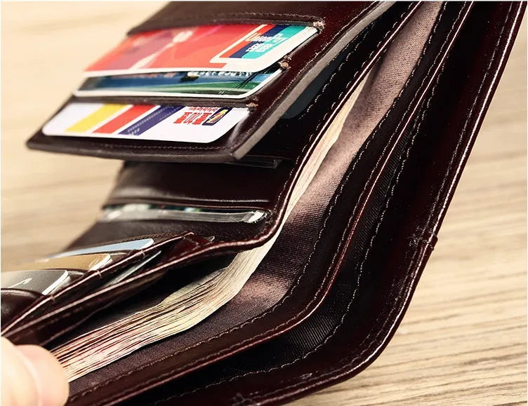 Men's black genuine leather bifold wallet open, showing eight card slots and a zipped coin compartment.