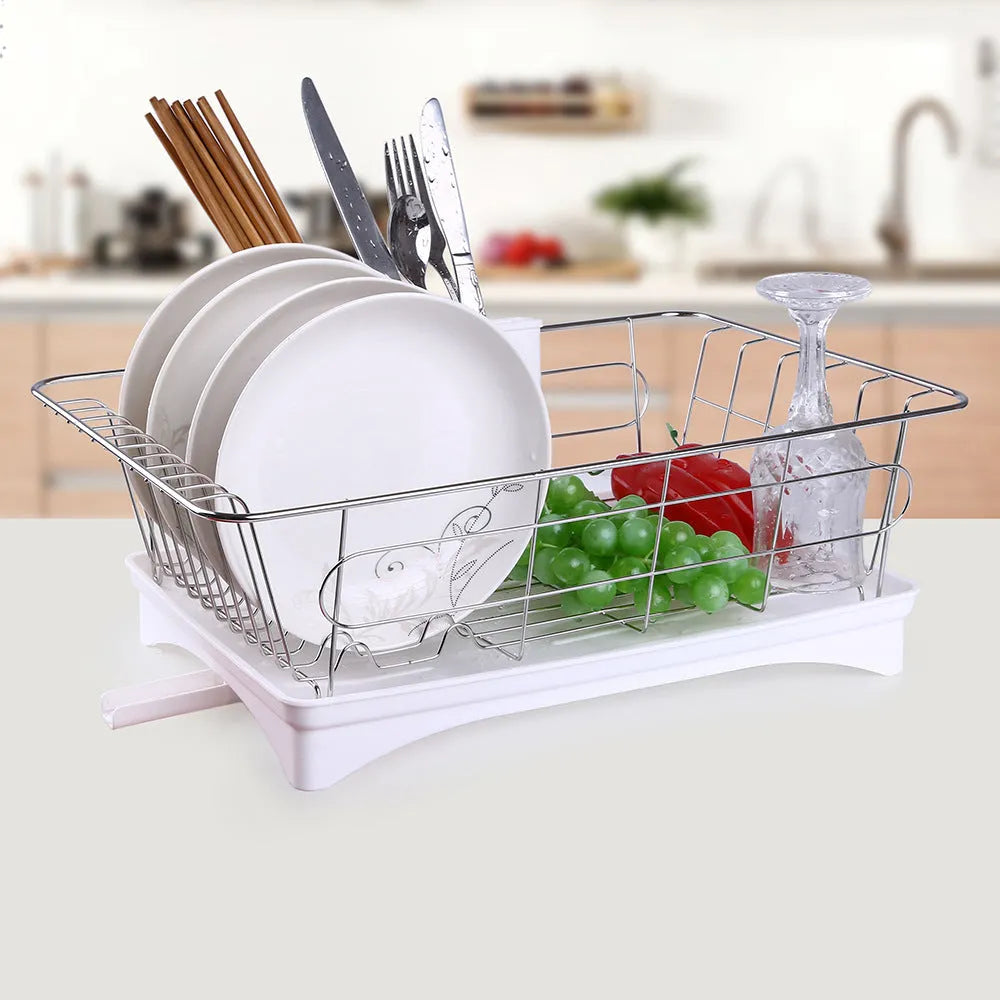 Black stainless steel dish drying rack with cutlery holder and drainboard on a kitchen counter.