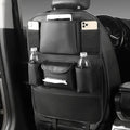 Black PU leather car seat back storage bag hanging on a grey car seat headrest.
