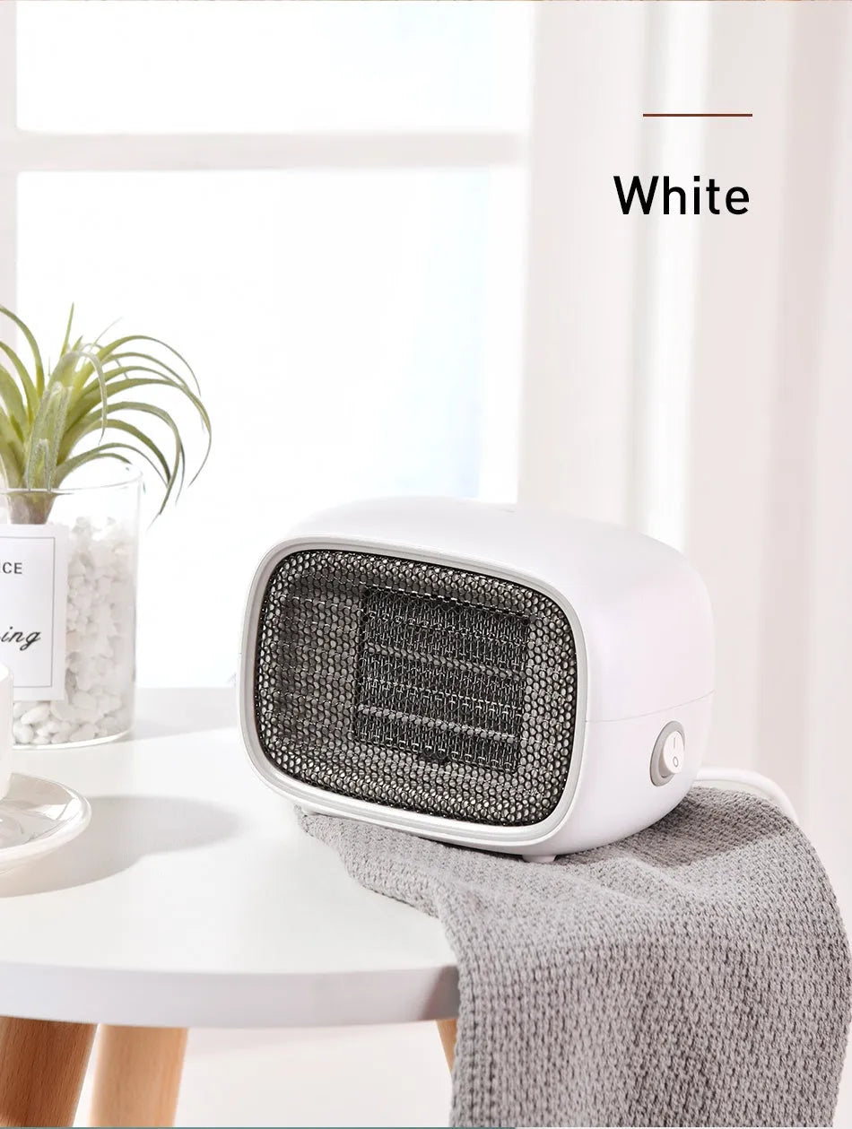 Small green portable ceramic fan heater on a desk showing its compact size.