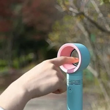 A compact portable bladeless fan with USB cable on a desk.