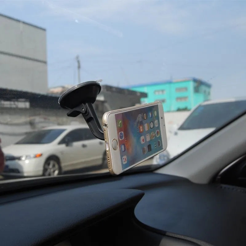 Classic black magnetic car phone holder mounted on a car dashboard, showing 360-degree rotation.