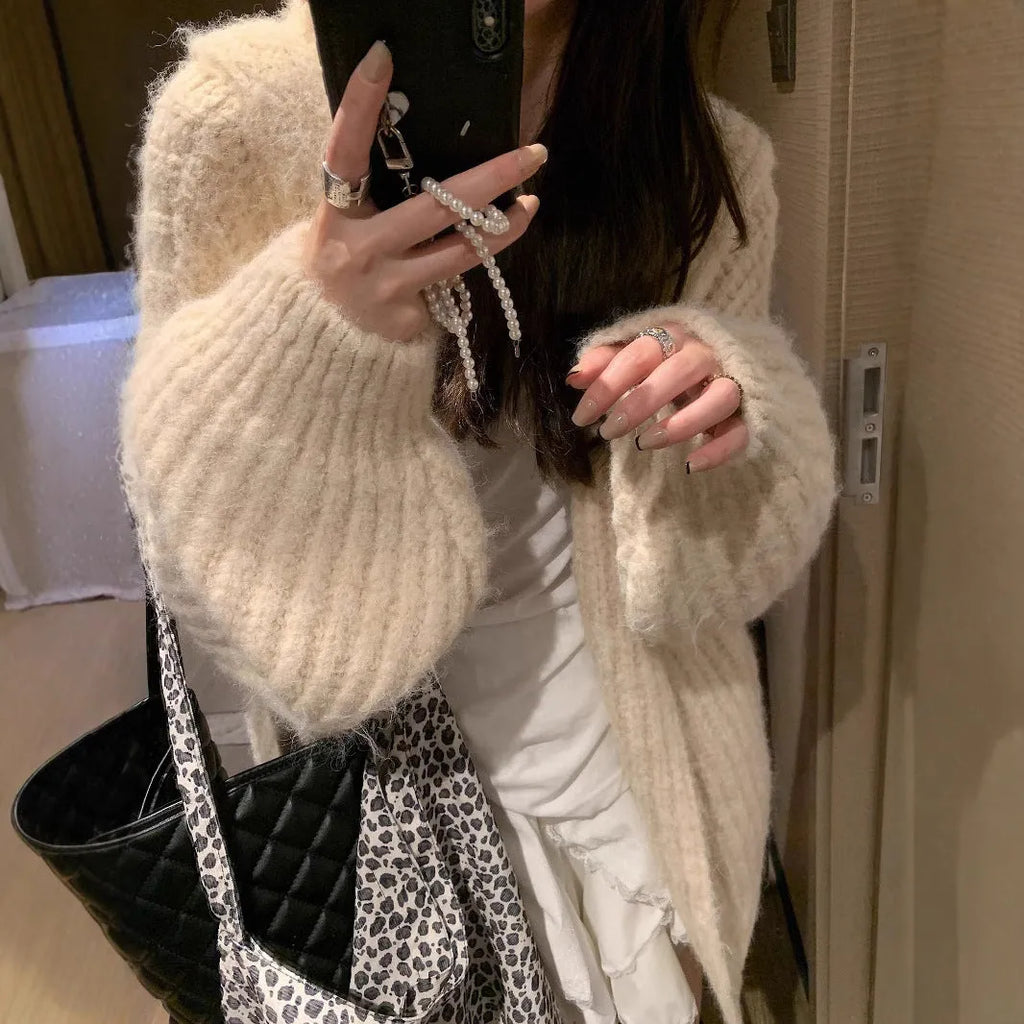 A woman wearing a loose-fit dark grey hooded cardigan made from thick acrylic blend fabric.