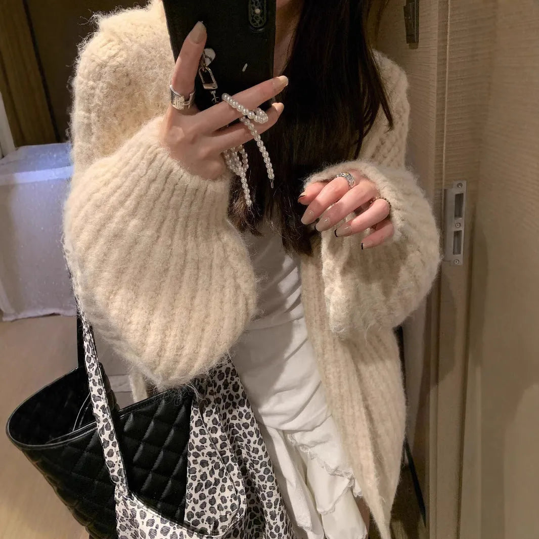A woman wearing a loose-fit dark grey hooded cardigan made from thick acrylic blend fabric.
