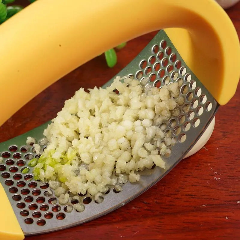Stainless steel garlic press with coloured ergonomic handle on a kitchen counter.