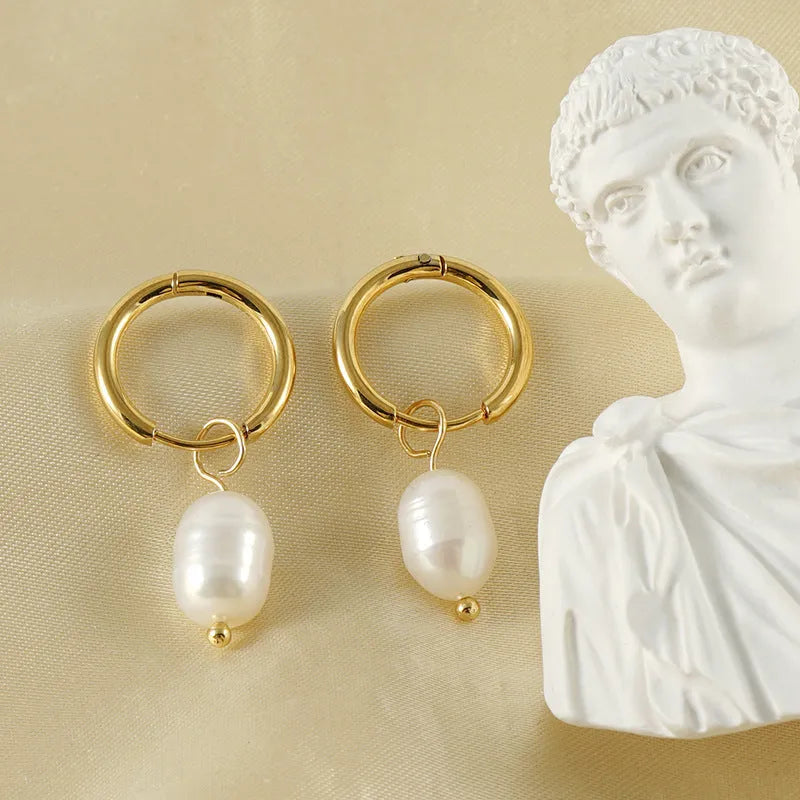 A pair of gold-colour geometric drop earrings with white pearl accents on a stainless steel post.