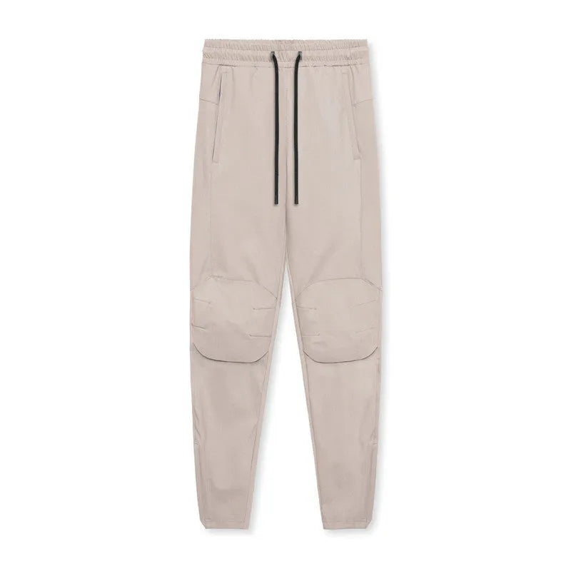 Men's grey loose-fit fitness trousers with ankle ties, made from quick-drying polyester fabric.