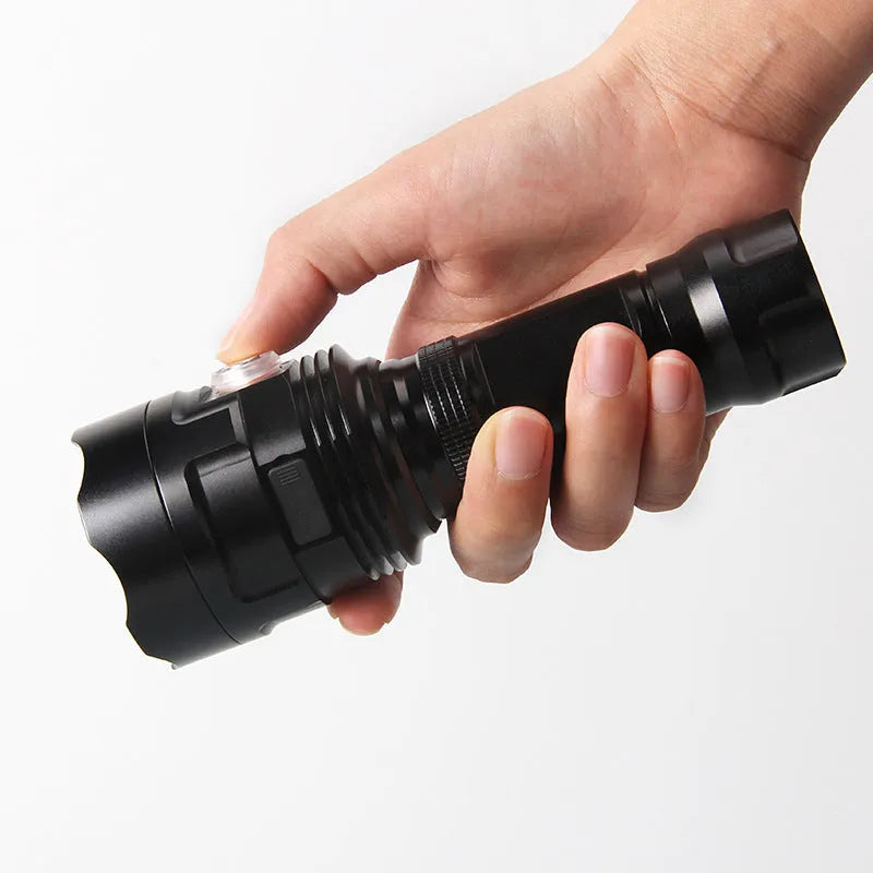 Black aluminium alloy tactical flashlight with large head, shown with USB cable and yellow packaging box.