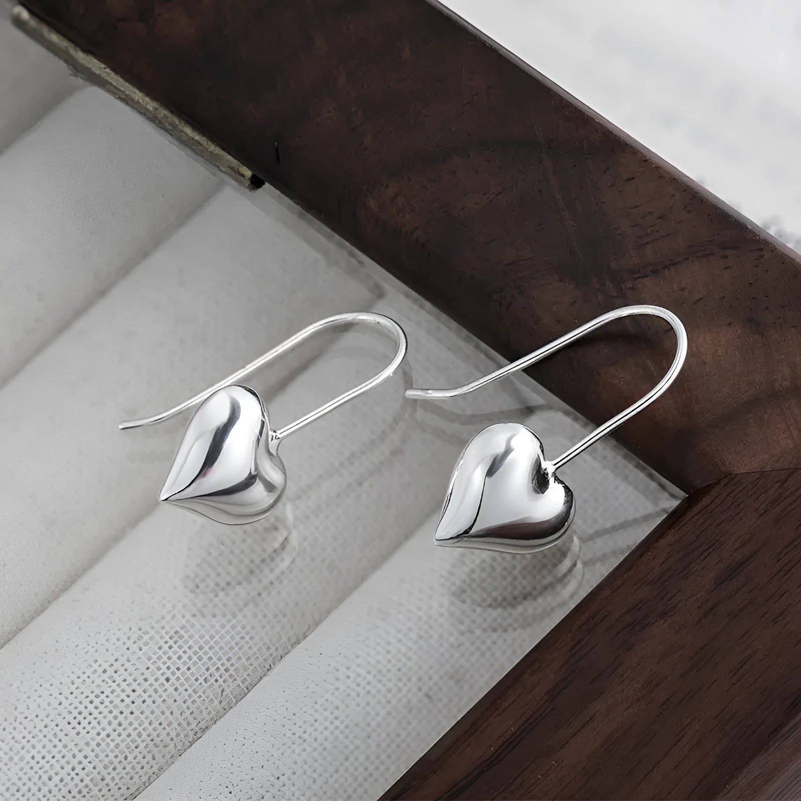 Silver Korean style heart-shaped earrings with a glossy three-dimensional design on a white background.