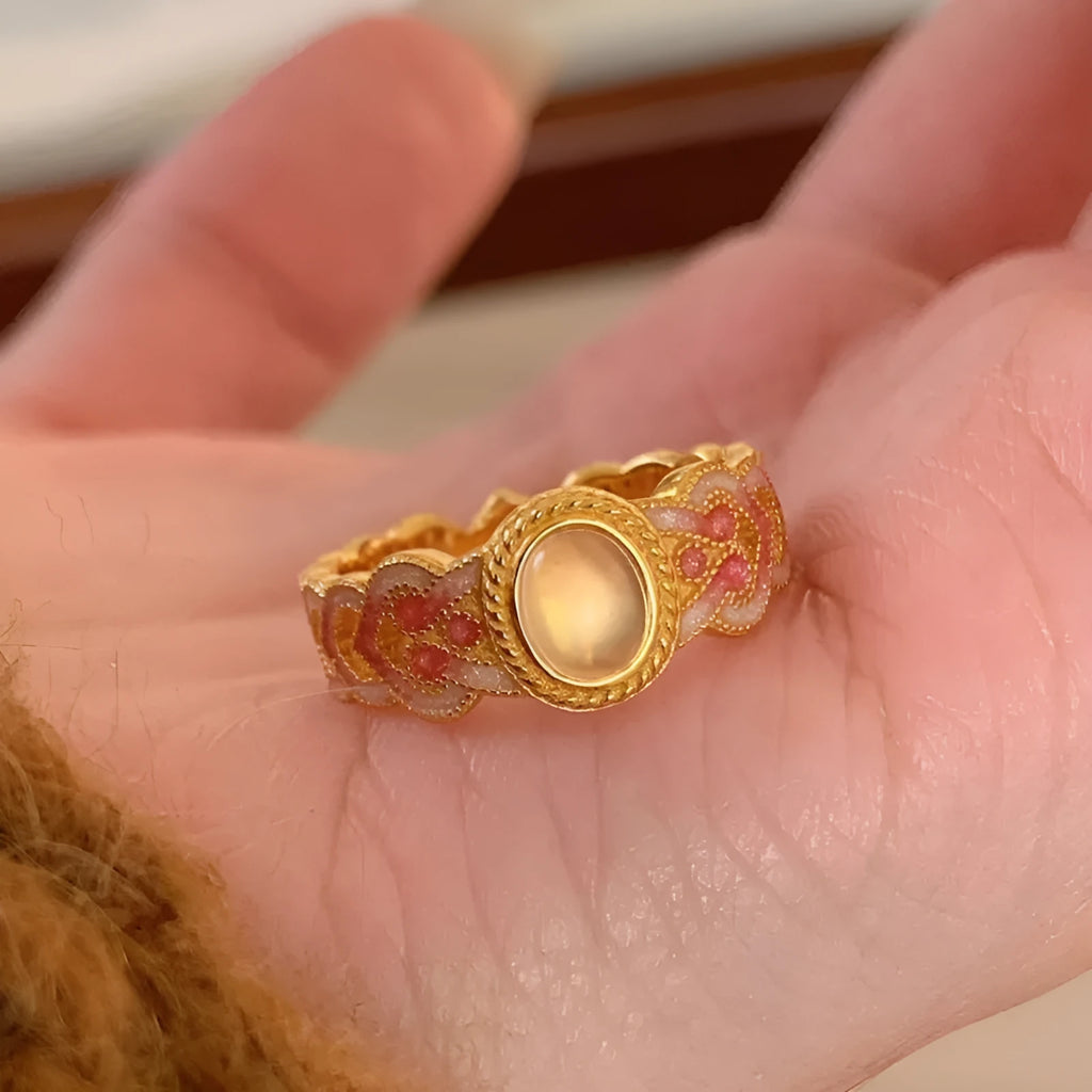 Close-up of a women's adjustable open ring with pink crystal enamel on a geometric gold-plated band.