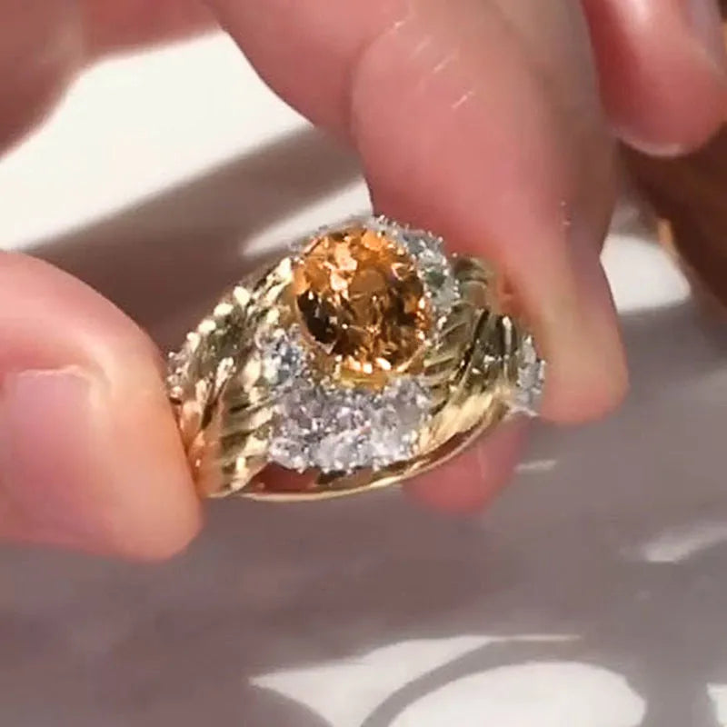 Gold-coloured embossed feather ring with geometric pattern and yellow zircon stones on a white background.