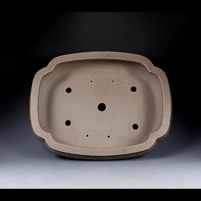 Handmade antique papaya-shaped purple clay flower pot on a wooden surface.