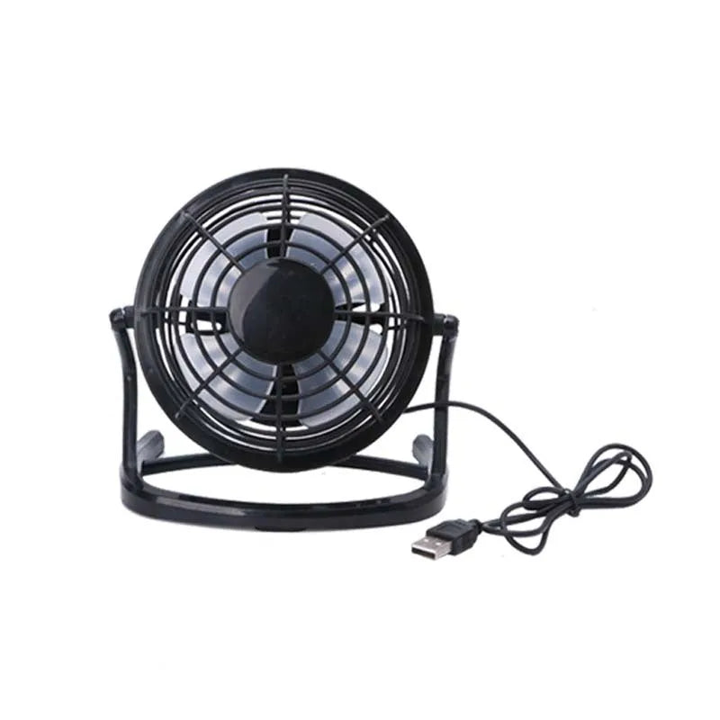 Small black and white USB desktop fan with adjustable stand on a desk next to a laptop.