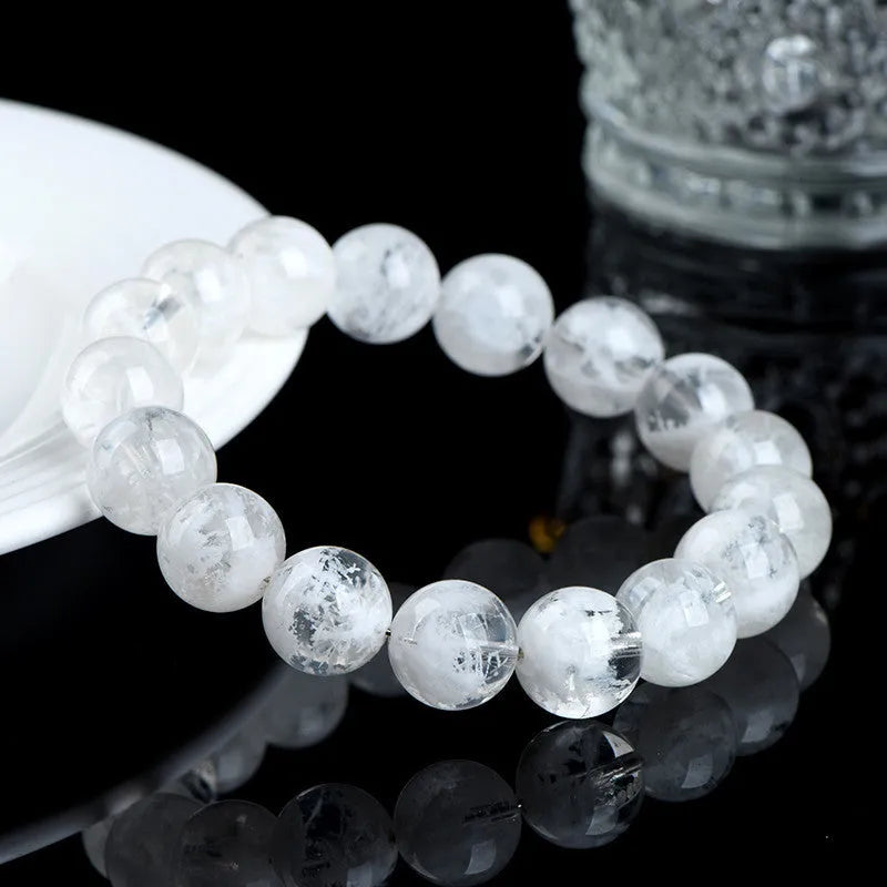 Women's natural blizzard snowflake round bead crystal bracelet with geometric design on a wrist.