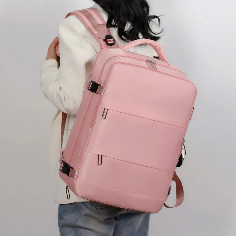 Large grey travel backpack with multiple compartments and an air pillow strap, shown next to a laptop.