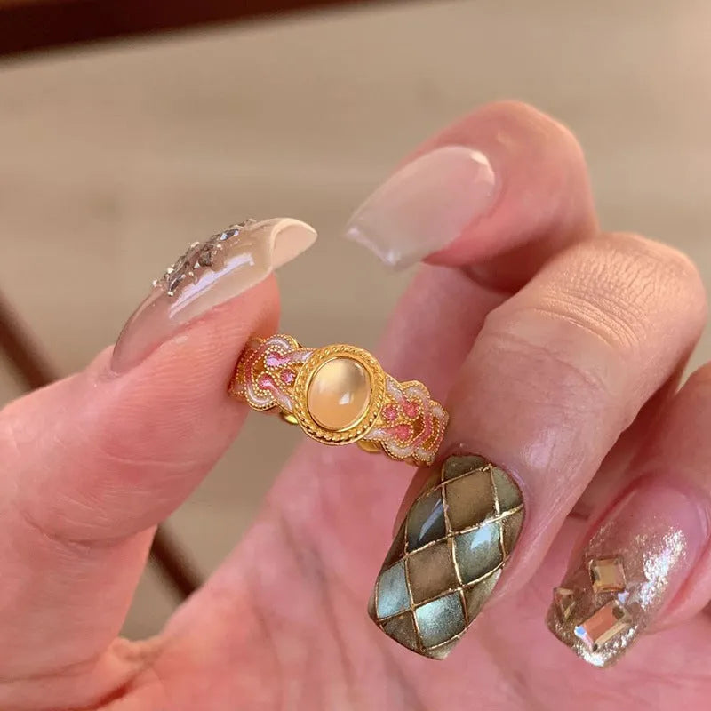 Close-up of a women's adjustable open ring with pink crystal enamel on a geometric gold-plated band.