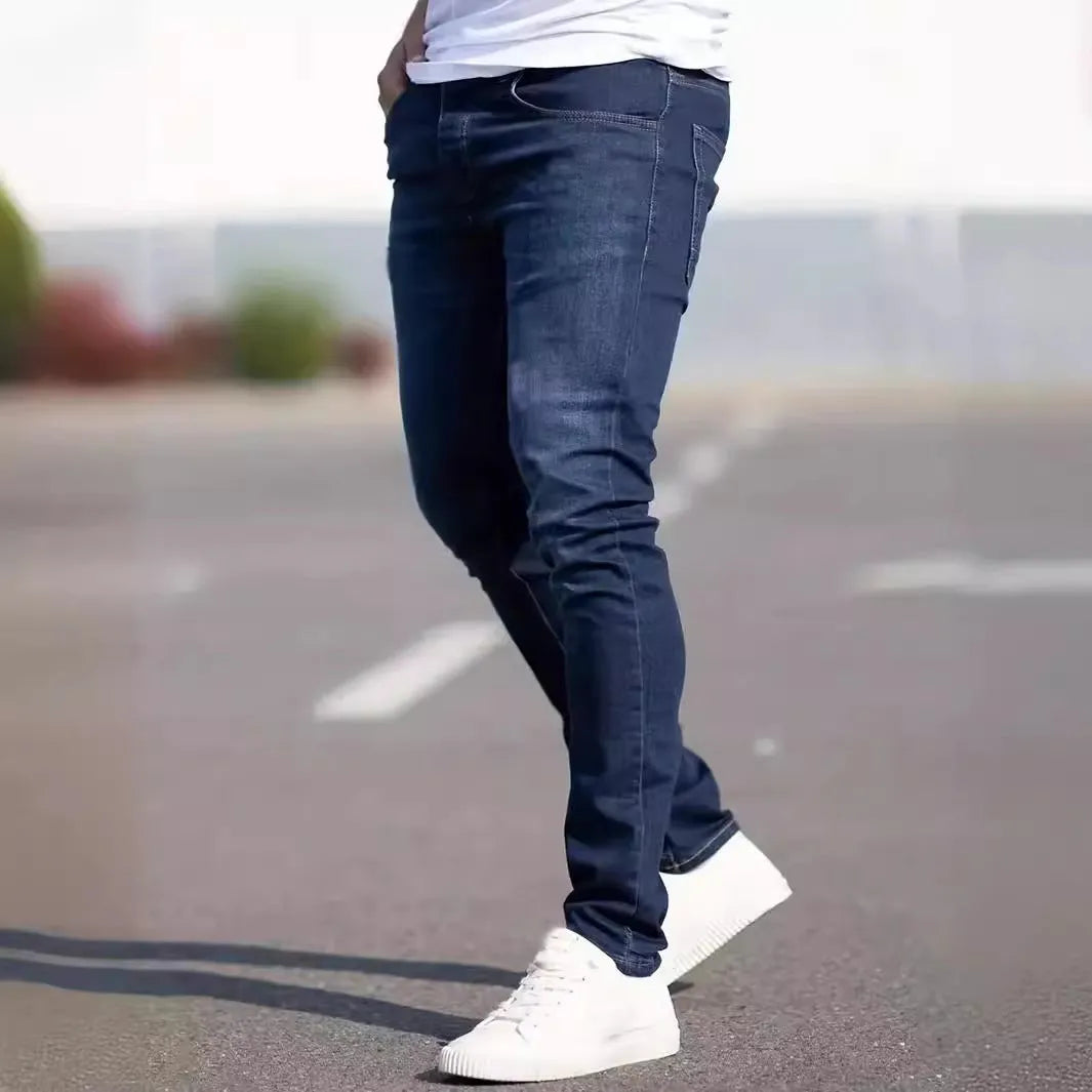 Men's dark blue skinny-fit cotton jeans with a mid-rise waist and zipper fly on a plain background.