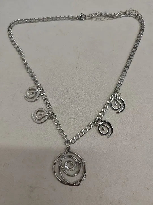 Gold spiral donut pendant necklace, matching bracelet and ear hooks set on a grey background.